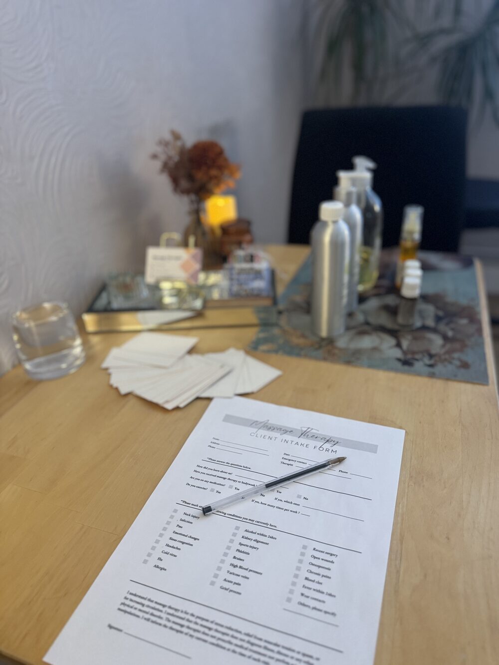Consultation form and massage oils set out before a treatment
